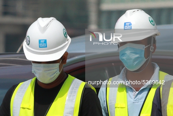 Indian and Sri Lankan construction workers walk out of a mega-construction site wearing  face masks following  the  Corona virus outbreak in...