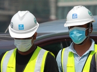 Indian and Sri Lankan construction workers walk out of a mega-construction site wearing  face masks following  the  Corona virus outbreak in...