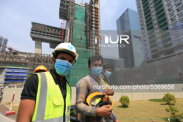 Indian and Sri Lankan construction workers walk out of a mega-construction site wearing  face masks following  the  Corona virus outbreak in...