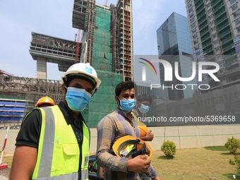 Indian and Sri Lankan construction workers walk out of a mega-construction site wearing  face masks following  the  Corona virus outbreak in...