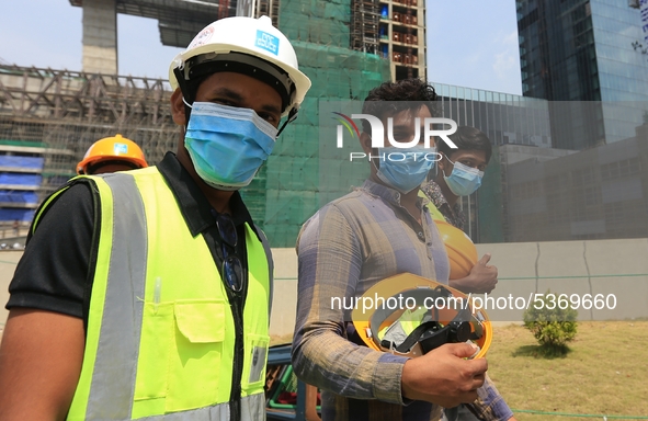 Indian and Sri Lankan construction workers walk out of a mega-construction site wearing  face masks following  the  Corona virus outbreak in...