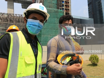 Indian and Sri Lankan construction workers walk out of a mega-construction site wearing  face masks following  the  Corona virus outbreak in...