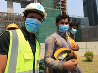 Indian and Sri Lankan construction workers walk out of a mega-construction site wearing  face masks following  the  Corona virus outbreak in...