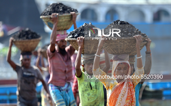 Bangladeshi laborers unload coal from boats  ahead of International Women's Day at the River Turag in Dhaka, Bangladesh, on March 7, 2020. 