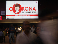 People walk past an electronic billboard displaying Coronavirus disease (COVID-19) safety awareness advertisement at a railway station on Ma...