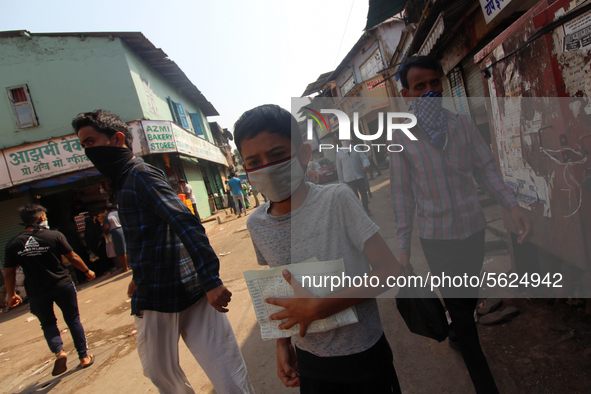 A boy wearing a face mask holds a list as he walks along a street in Mumbai, India on April 11, 2020. India continues in nationwide lockdown...