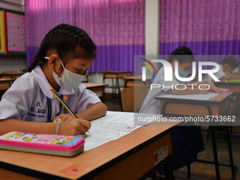 Elementary school students wearing face masks in social distancing as a preventive measure in a class is a demonstration of learning amid th...