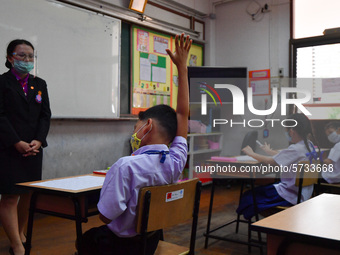 Elementary school students wearing face masks and a teacher wearing a face shield in social distancing as a preventive measure in a class is...