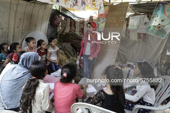 A Palestinian school girl Fajr Hmaid, 13, teaches her neighbours' children an Arabic language lesson as schools are shut due to the coronavi...