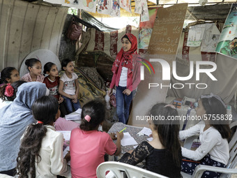 A Palestinian school girl Fajr Hmaid, 13, teaches her neighbours' children an Arabic language lesson as schools are shut due to the coronavi...