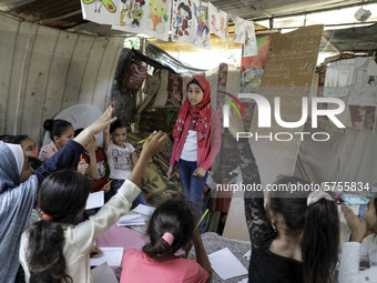 A Palestinian school girl Fajr Hmaid, 13, teaches her neighbours' children an Arabic language lesson as schools are shut due to the coronavi...