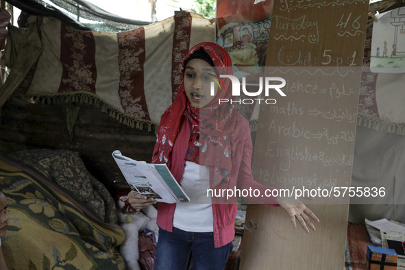 A Palestinian school girl Fajr Hmaid, 13, teaches her neighbours' children an Arabic language lesson as schools are shut due to the coronavi...