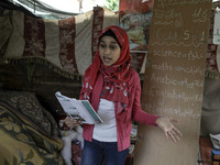 A Palestinian school girl Fajr Hmaid, 13, teaches her neighbours' children an Arabic language lesson as schools are shut due to the coronavi...