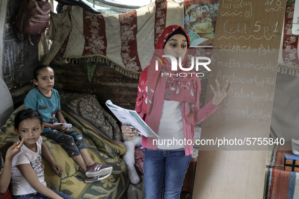 A Palestinian school girl Fajr Hmaid, 13, teaches her neighbours' children an Arabic language lesson as schools are shut due to the coronavi...