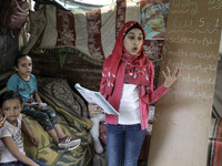 A Palestinian school girl Fajr Hmaid, 13, teaches her neighbours' children an Arabic language lesson as schools are shut due to the coronavi...