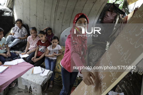 A Palestinian school girl Fajr Hmaid, 13, teaches her neighbours' children an Arabic language lesson as schools are shut due to the coronavi...