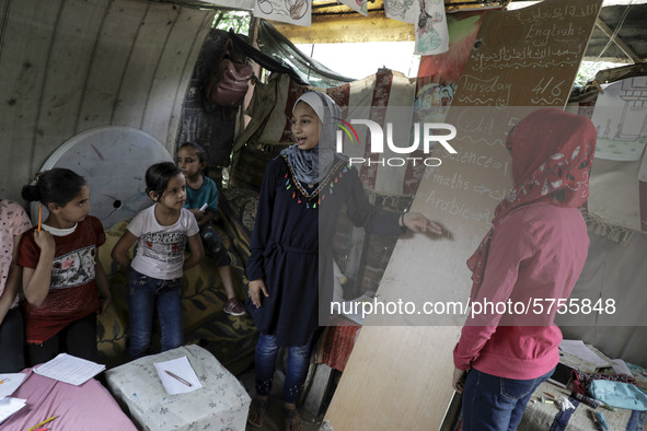 A girl reads out a text as Palestinian student Fajr Hmaid, 13, teaches her neighbours' children an Arabic language lesson as schools are shu...