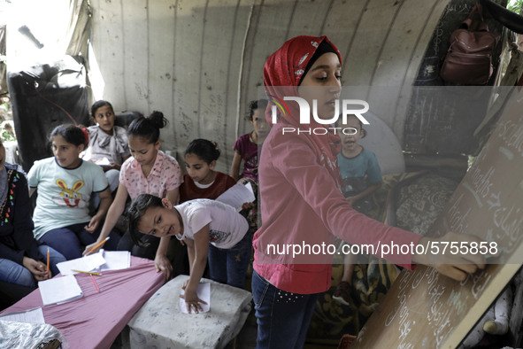 A Palestinian school girl Fajr Hmaid, 13, teaches her neighbours' children an Arabic language lesson as schools are shut due to the coronavi...