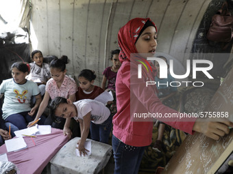 A Palestinian school girl Fajr Hmaid, 13, teaches her neighbours' children an Arabic language lesson as schools are shut due to the coronavi...