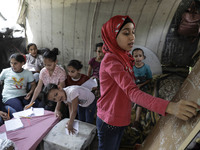 A Palestinian school girl Fajr Hmaid, 13, teaches her neighbours' children an Arabic language lesson as schools are shut due to the coronavi...