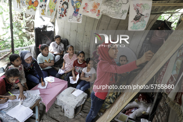 A Palestinian school girl Fajr Hmaid, 13, teaches her neighbours' children an Arabic language lesson as schools are shut due to the coronavi...