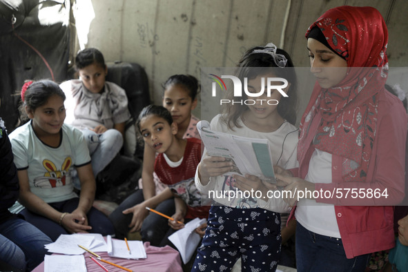 A Palestinian school girl Fajr Hmaid, 13, teaches her neighbours' children an Arabic language lesson as schools are shut due to the coronavi...