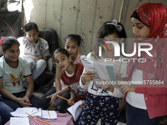 A Palestinian school girl Fajr Hmaid, 13, teaches her neighbours' children an Arabic language lesson as schools are shut due to the coronavi...