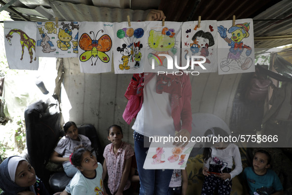 A Palestinian school girl Fajr Hmaid, 13, teaches her neighbours' children an Arabic language lesson as schools are shut due to the coronavi...