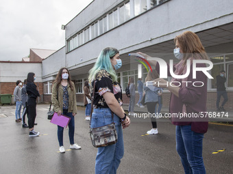 A school worker takes the temperature of each student before entering the classroom in Norena, Spain, on June 8, 2020. Spanish high school s...