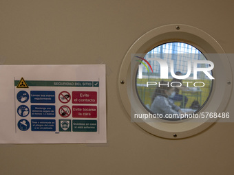 Two students receive a refresher class through a window with a sign indicating the sanitary rules to follow to avoid the coronavirus in Nore...