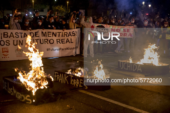 Nissan employees burn mock coffins while holding a banner reading ''Stop lies, we demand a real future'' during a protest against the closur...