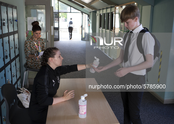   A teacher gives Year 10 pupils hand sanitizer. Ortu Gable Hall School in Corringham, Essex return after a long break due to the COVID-19 p...