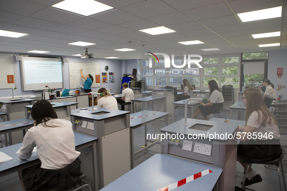   A teacher at the front of the class teaching a group of Year 10 pupils. Ortu Gable Hall School in Corringham, Essex return after a long br...