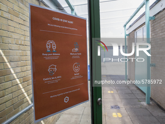   A COVID-19 poster on the door with footprints leading into the distance. Ortu Gable Hall School in Corringham, Essex return after a long b...