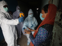 A healthcare worker checks the temperature of a woman during a medical check-up in Mumbai, India on July 01, 2020. India is the fourth worst...