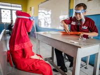 A teacher checking document of a little girl participant for the selection test for entering the school at Depok, West Java, Indonesia, on J...