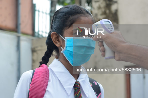 A school official checks the temperature of a student after their school after 115 days, the school that was shut down during the COVID-19 l...