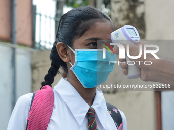 A school official checks the temperature of a student after their school after 115 days, the school that was shut down during the COVID-19 l...