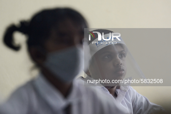 A student wearing a face shield sits in a classroom after their school after 115 days, the school that was shut down during the COVID-19 loc...