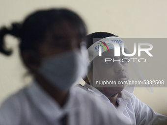 A student wearing a face shield sits in a classroom after their school after 115 days, the school that was shut down during the COVID-19 loc...