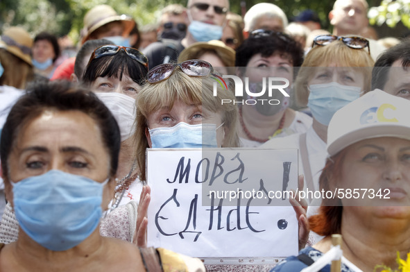 A woman holds a poster reading like 'The language unites!' during a rally in support Ukrainian language and against a bill which offers to e...