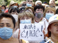 A woman holds a poster reading like 'The language unites!' during a rally in support Ukrainian language and against a bill which offers to e...