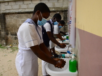 High school students wash their hands in a wash hand basin at the entrance of Ireti Junior Grammar Schol, Ikoyi, Lagos on August 3, 2020 on...