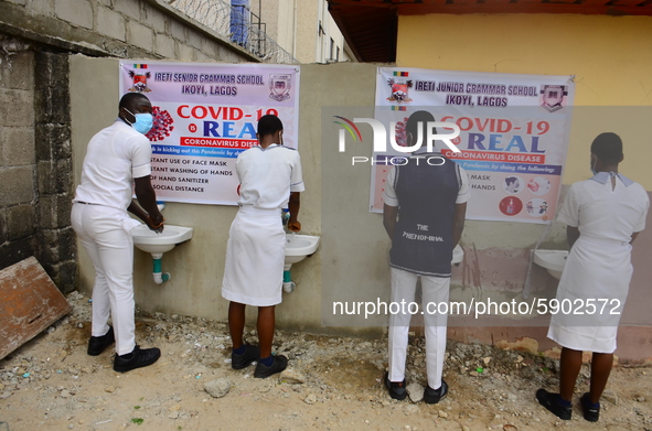 High school students wash their hands in a wash hand basin at the entrance of Ireti Junior Grammar Schol, Ikoyi, Lagos on August 3, 2020 on...