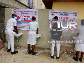 High school students wash their hands in a wash hand basin at the entrance of Ireti Junior Grammar Schol, Ikoyi, Lagos on August 3, 2020 on...