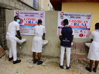 High school students wash their hands in a wash hand basin at the entrance of Ireti Junior Grammar Schol, Ikoyi, Lagos on August 3, 2020 on...