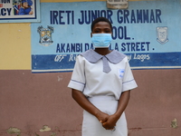 A High school student with a face mask pose for a photo at the entrance of Ireti Junior Grammar Schol, Ikoyi, Lagos on August 3, 2020 on the...