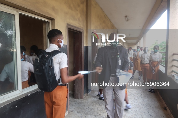 Final year students of Agidingbi Senior Grammar School, Ikeja, Lagos, Nigeria receive facemask from a teacher as they resume school after CO...