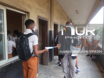 Final year students of Agidingbi Senior Grammar School, Ikeja, Lagos, Nigeria receive facemask from a teacher as they resume school after CO...