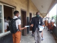 Final year students of Agidingbi Senior Grammar School, Ikeja, Lagos, Nigeria receive facemask from a teacher as they resume school after CO...